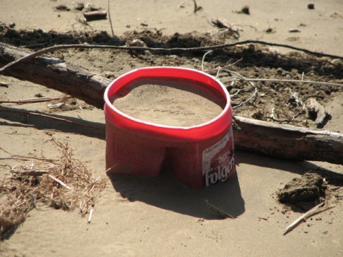 sand-filled, half-buried, red plastic coffee container, 2/2011