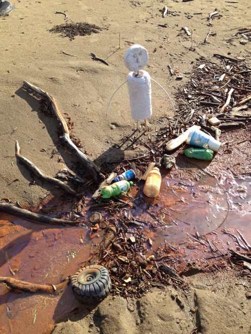 Benchmark figure posed near river trash, Falls of the Ohio, Nov. 2014